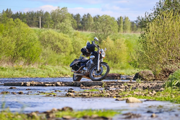 Zwarte motorfiets staat op het stenen plateau aan de oever van de rivier op een zonnige dag