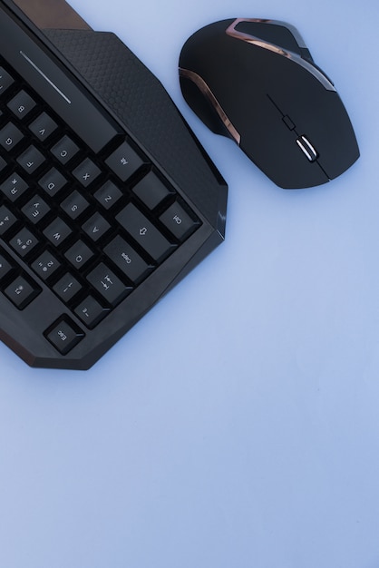 Zwarte muis en toetsenbord op een blauwe achtergrond, bovenaanzicht. Werkplek, muis en toetsenbord plat neergelegd.