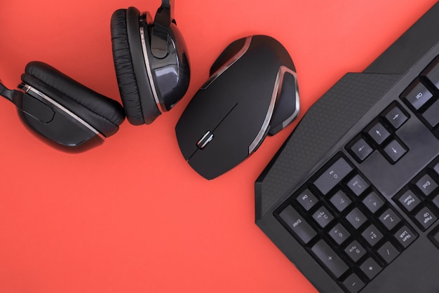 Zwarte muis, het toetsenbord, de koptelefoon zijn geïsoleerd op een rode achtergrond