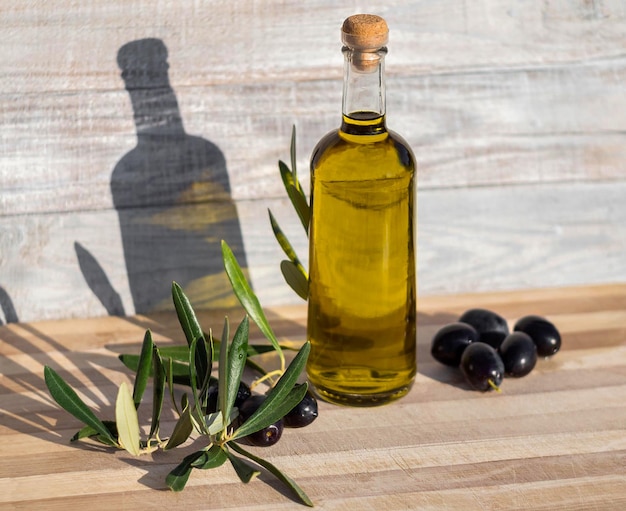 Zwarte olijven en een fles met natuurlijke Griekse olijfolie een houten achtergrond in Griekenland