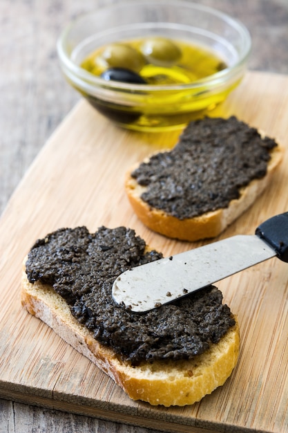 Zwarte olijventapenade met ansjovis, knoflook en olijfolie op houten lijst