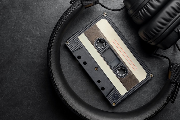 Zwarte onear hoofdtelefoons en audio tape compact cassette op leisteen achtergrond