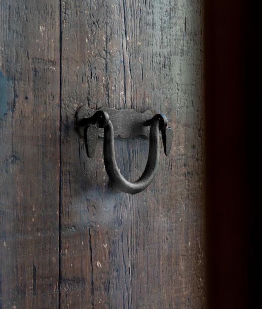 Zwarte oude deurklink over een bruine houten deur