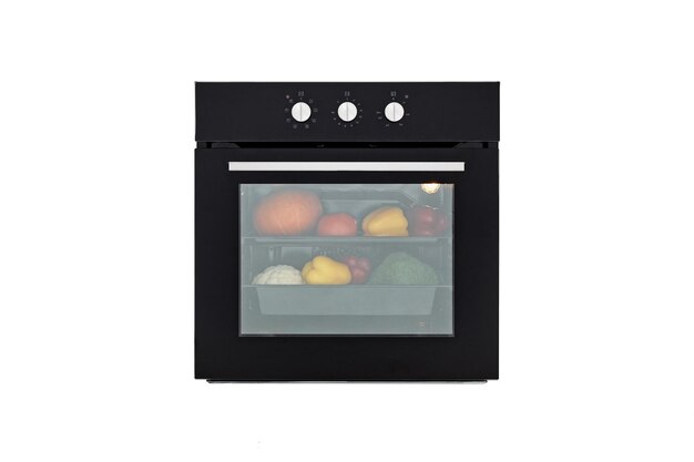 Zwarte oven met gesloten deur en groenten voor het roosteren vooraanzicht geïsoleerd op wit