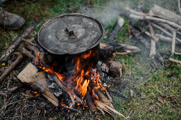 Zwarte pan met een deksel op het vuur in het bos in de winter in Georgië winter