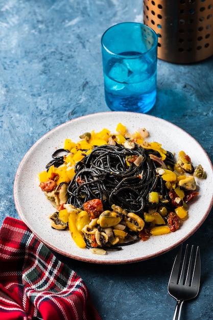 Zwarte pasta met zeevruchten, ansjovis, tomaten en paprika.