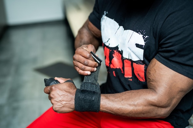 Zwarte pet en T-shirt, pauze. Grote sterke man fitness model rusten in de sportschool. leunde tegen de simulator sportuitrusting.