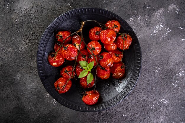 Zwarte plaat met gekonfijte tomaten op donkere achtergrond.