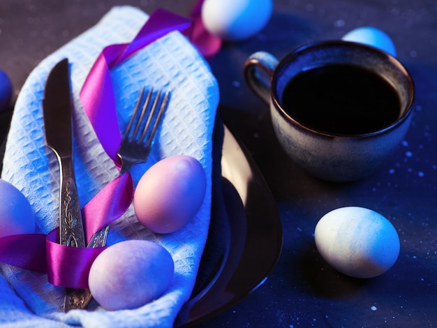 Zwarte plaat met paaseieren op een stenen donkere tafel neon stijl gekleurd licht espressokopje