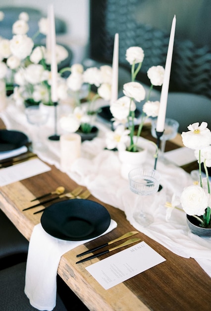 Zwarte plaat staat naast goud bestek op een feestelijke tafel voor een glas en boeketten wit