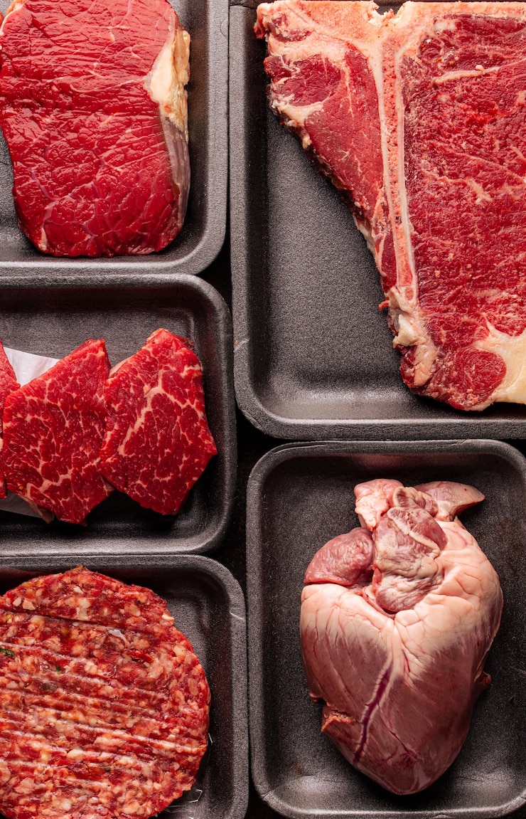 Foto zwarte plastic verpakkingstrays van supermarkt met verschillende soorten verse rauwe vleesdelen, verse beefbeef steaks en verschillende soorten vlees in dozen van bovenaf