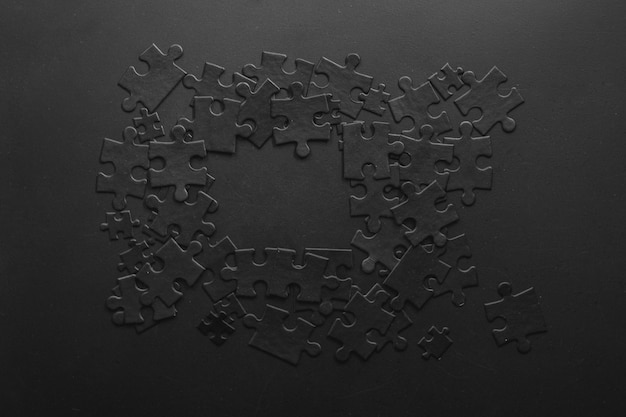 Zwarte puzzels willekeurig gevouwen in een vorm die een frame vormt met ruimte voor uw tekst op een donkere achtergrond