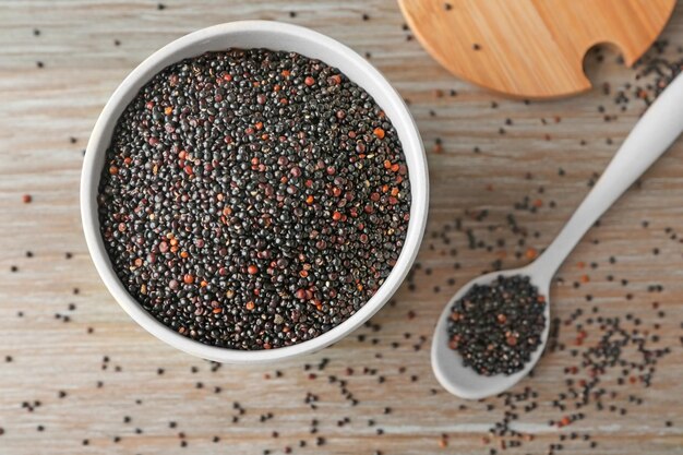 Zwarte quinoa in keramische kom en lepel op keukentafel