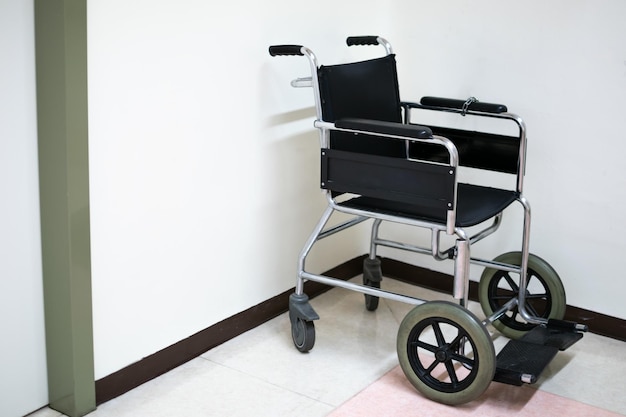 Foto zwarte rolstoel op de vloer van het ziekenhuis met witte achtergrond