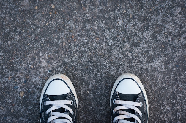 Zwarte sneakers met hipster man op beton