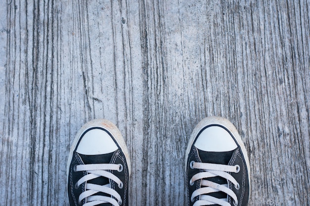 Zwarte sneakers met hipster man op beton