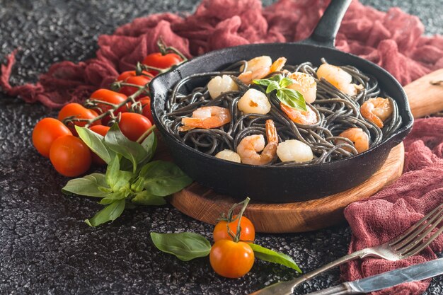 Zwarte spaghetti met garnalen en sint-jakobsschelp in koekenpan