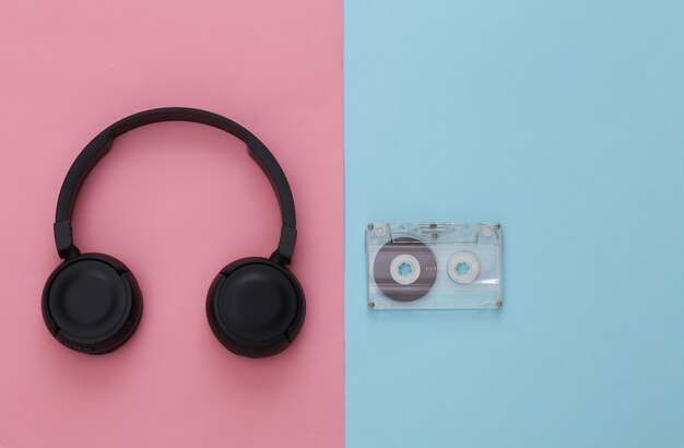 Zwarte stereohoofdtelefoon met retro audiocassette op roze blauw pastel