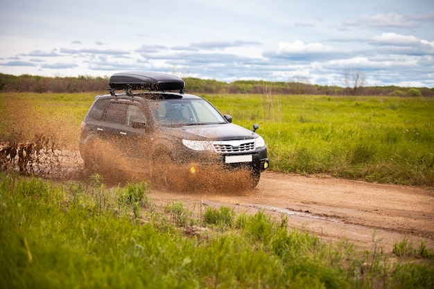 Zwarte Subaru Forester beweegt op vuile bosweg en maakt veel waterspatten