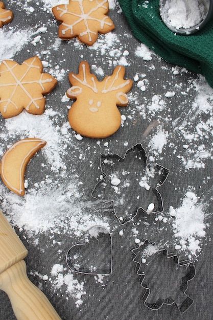 Foto zwarte tafel met meel en zelfgemaakte kerstkoekjes groene keukenhanddoek en rolspeld