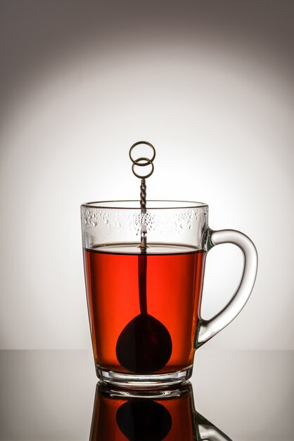 Zwarte thee in een glazen beker met een handvat en een theelepel. Foto genomen in studio