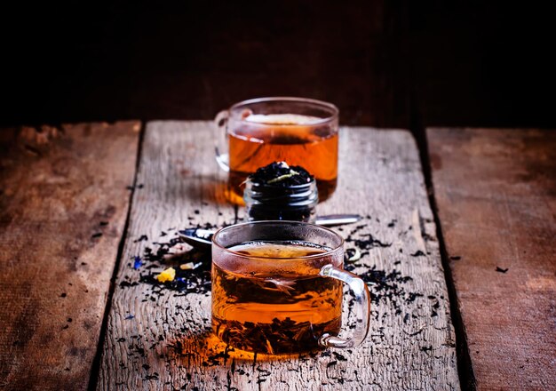 Zwarte thee met bloemenkorenbloem en gedroogd fruit in glazen bekers op de oude houten achtergrond selectieve focus