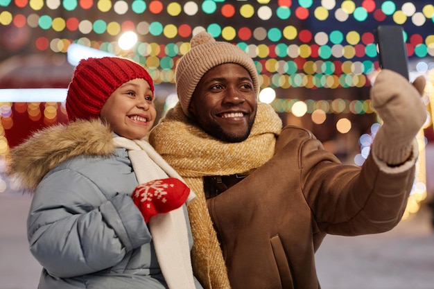 Zwarte vader en dochter nemen een selfie foto in de winter