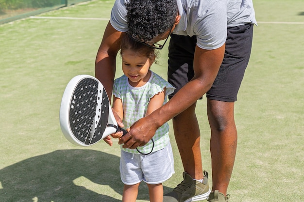 Zwarte vader leert dochter paddletennis spelen