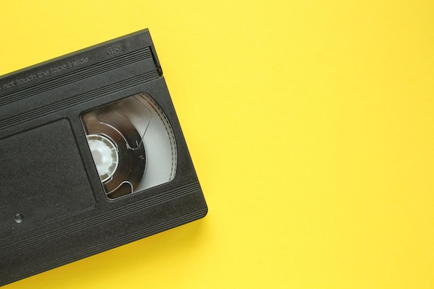 Zwarte VHS-videorecordercassette op gele achtergrond. Oude verouderde technologie voor bandrecordi