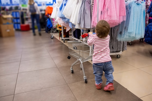 Zwarte vrijdag winkelen schattige peuterstandaard met winkelwagentje voor hangers met kleding