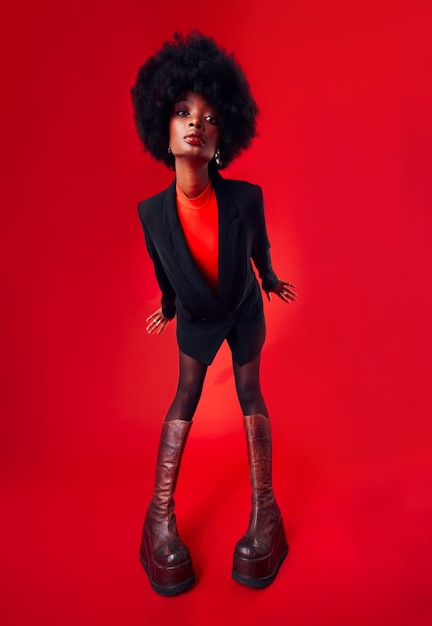 Zwarte vrouw afro en haar met mode en stijl edgy met merkkleding en gen z geïsoleerd op rode achtergrond mockup ruimte stijlvolle kleding en trendy afrikaans model met kapsel in een studio