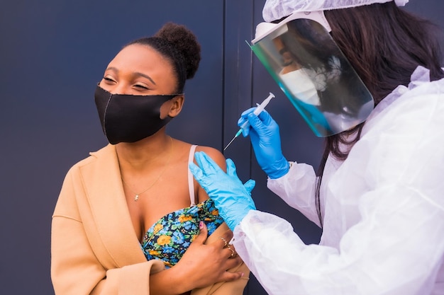Zwarte vrouw die de injectie van het coronavirusvaccin krijgt van een arts