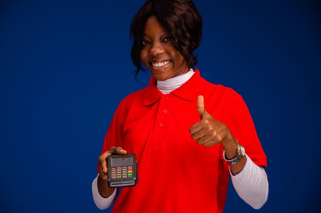 Zwarte vrouw die een verkooppuntapparaat gebruikt en deed duimen omhoog