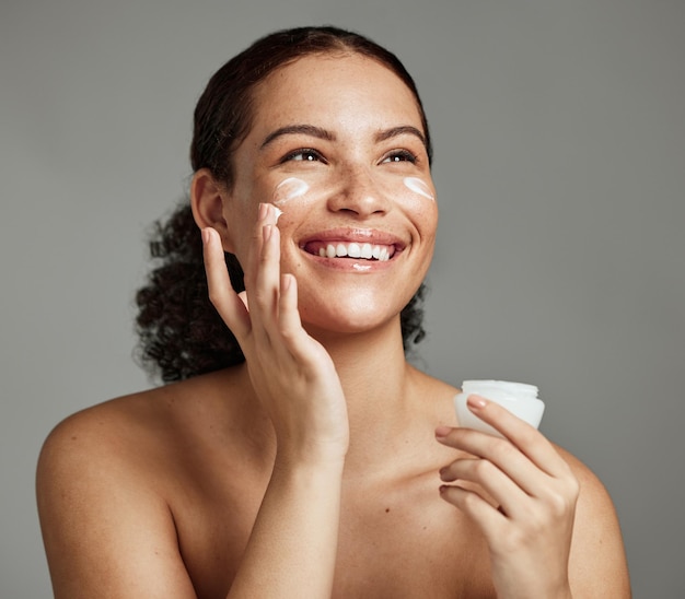 Foto zwarte vrouw glimlach en gezicht schoonheidscrème voor huidverzorging wellness glans cosmetica dermatologie en salon spa product in studio afrikaans meisje spf lotion en zelfzorg geluk voor luxe gezichtsgloed