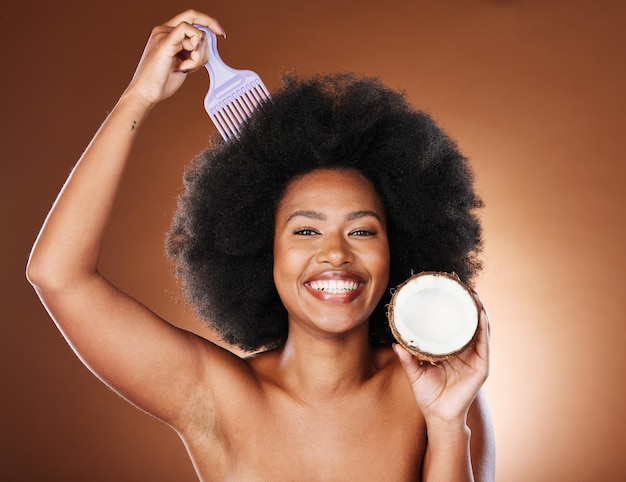 Zwarte vrouw haarverzorging kam en kokosnoot voor schoonheid in studio geïsoleerd op bruine achtergrond Wellness gezond en vrouwelijk model met tropisch fruit en kokosolie voor kapsel of afro haarbehandeling
