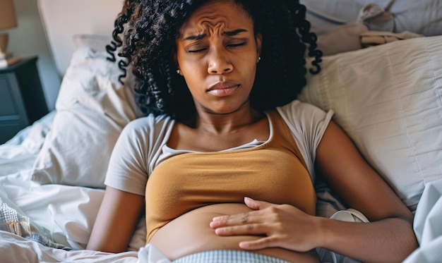 zwarte vrouw in bed die lijdt aan buikpijn menstruatie en maagproblemen