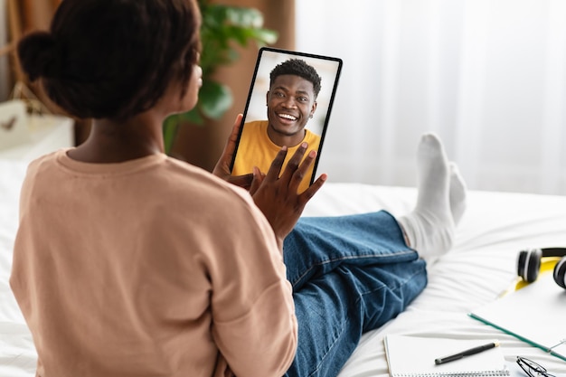 Zwarte vrouw met behulp van digitale tablet praten met vriendje achteraanzicht