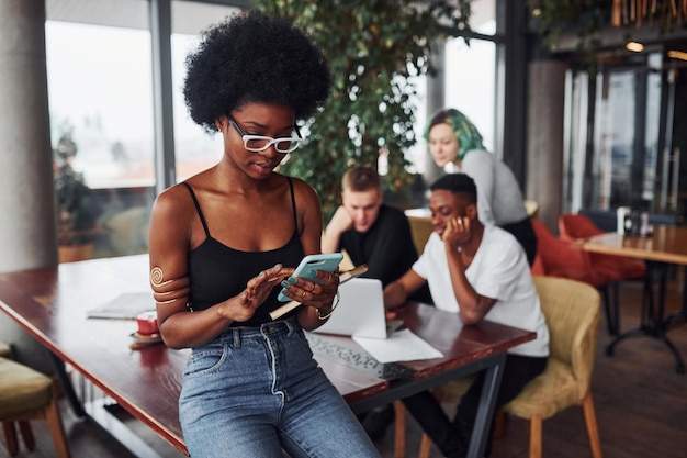 Zwarte vrouw met een smartphone die voor een groep multi-etnische mensen staat