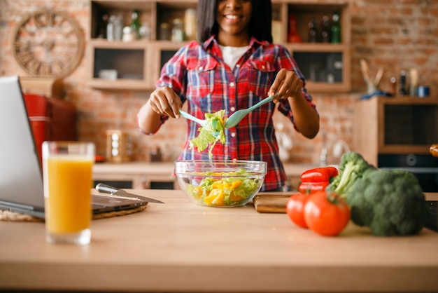 Zwarte vrouw ontbijt koken op de keuken.