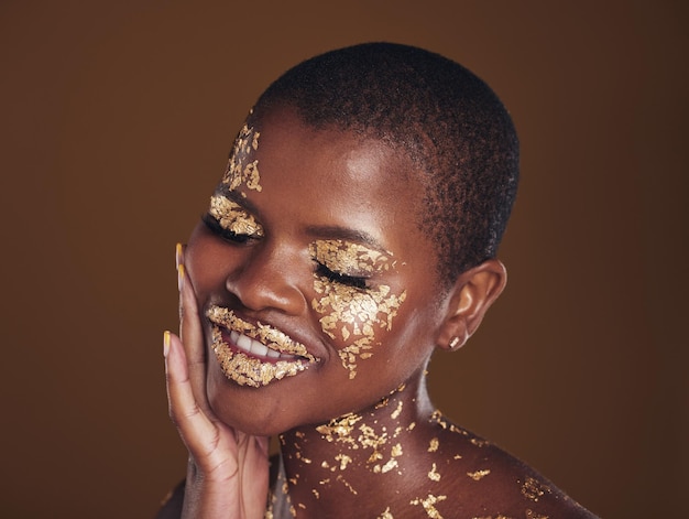 Zwarte vrouw relax en gouden make-up met luxe dermatologie en huidverzorgingsmasker met glitter Sparkle glimlach en schoonheid met vrolijke glans en glans van cosmetica en model in een studio met gezichtskunst