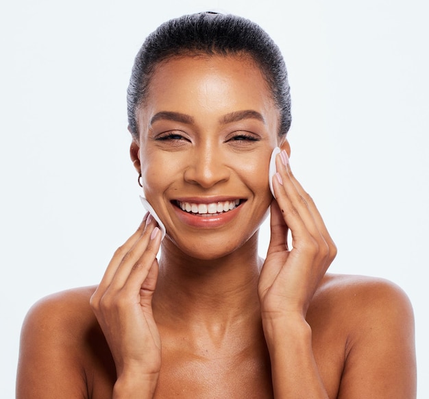 Zwarte vrouw schoonheid en katoen op gezicht portret in studio voor dermatologie cosmetica en natuurlijke huid Gelukkig esthetisch model reiniging make-up voor zelfzorg gezichtsgloed geïsoleerd op een witte achtergrond