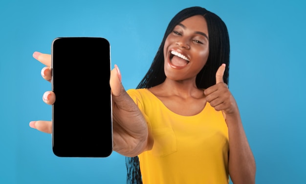 Zwarte vrouw weergegeven: smartphone met leeg scherm en duim omhoog