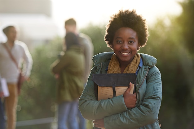 Foto zwarte vrouwelijke universiteitsstudent en portret met boek op de campus voor het voorbereiden van informatie en aantekeningen over onderzoek outdoor college en kennis met advies voor test en opdracht indiening