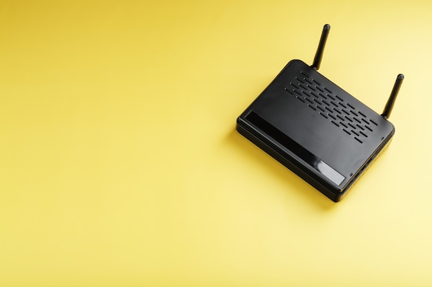 Zwarte Wi-Fi-router op een gele achtergrond met vrije ruimte. Isoleer, bovenaanzicht. Online