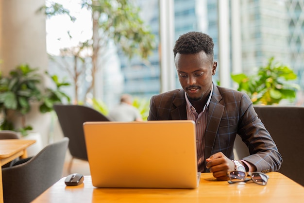 Zwarte zakenman die laptopcomputer met behulp van bij coffeeshop