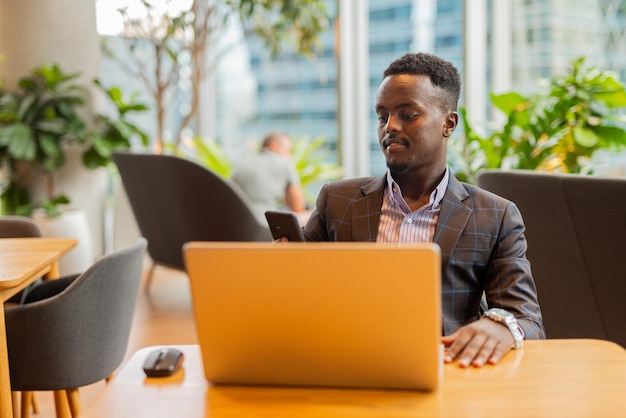 Zwarte zakenman die laptopcomputer met behulp van bij coffeeshop