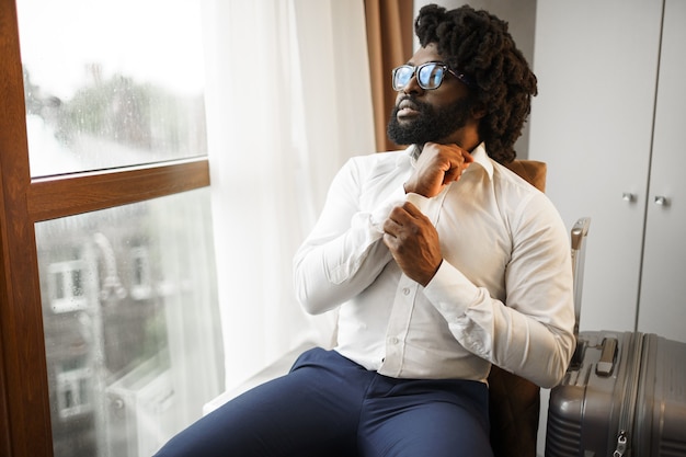 Foto zwarte zakenman zit in de buurt van het raam in de hotelkamer