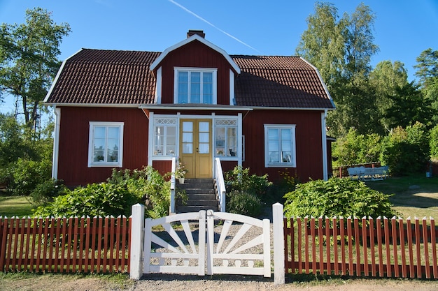 Foto zweeds rood en wit traditioneel huis in smalland white omheining groene tuin blauwe lucht