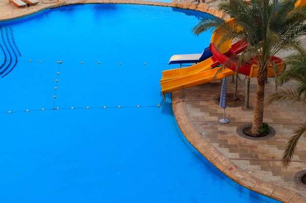Zwembad met waterglijbaan in het tropische zomerresort. Uitzicht van boven