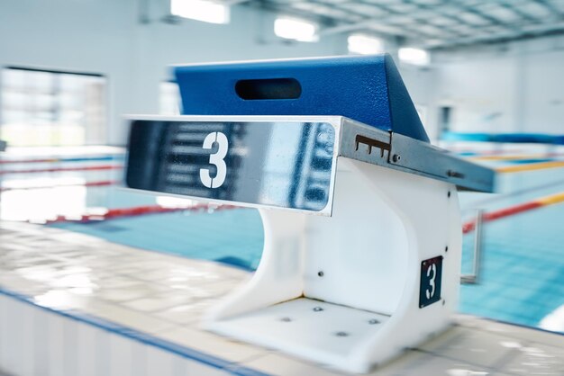 Zwembadsporten en podiumnummer door water voor training en training voor triatloncompetitie Fitnessmotivatie en drie op professioneel startblok voor duikrace en duiken